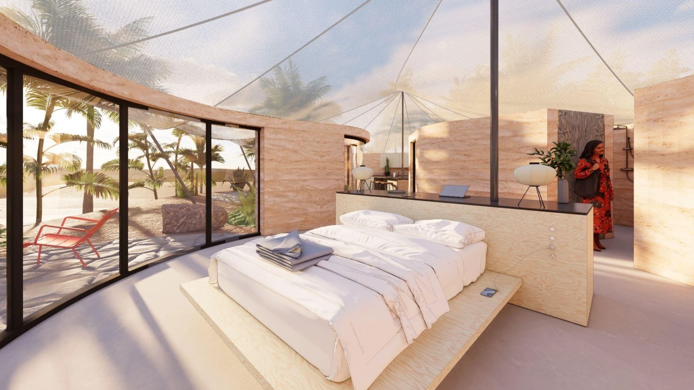Platform bed under the translucent canopy, palms and a red lounge chair beyond the curved glass