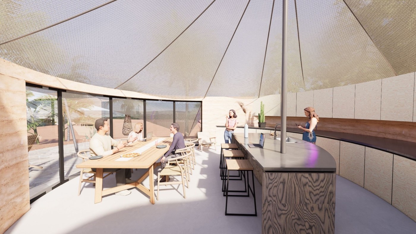Round common room under the tent canopy with a long dining table and curved kitchen island