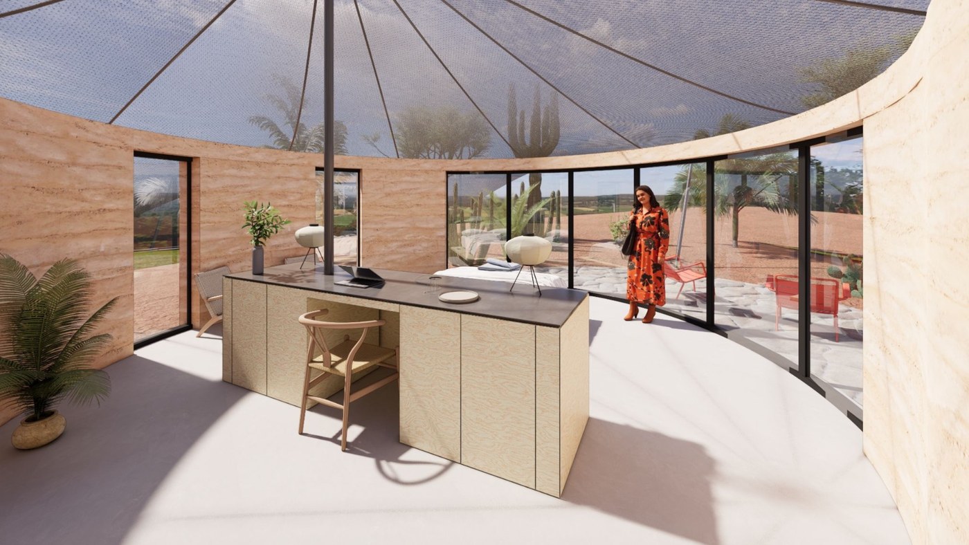 Suite interior with an island desk, curved glass wall, and views to the desert garden patio