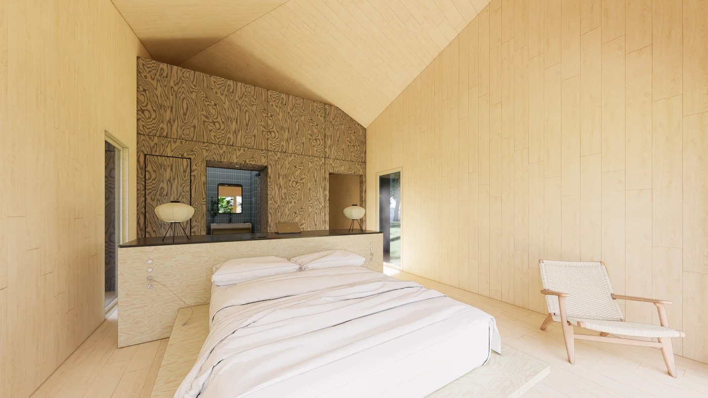 Bedroom under the vaulted ceiling, with the plywood headboard island and a glimpse of the blue-tiled bath beyond